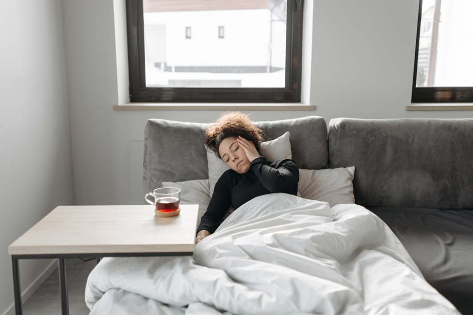 Woman lying in bed, holding her head