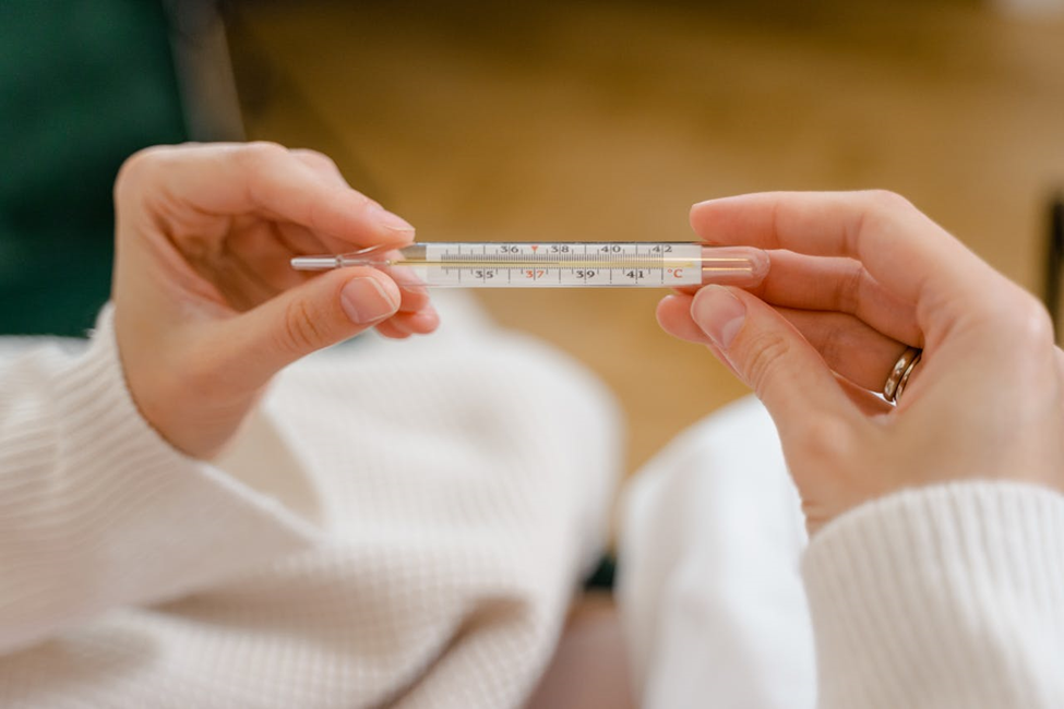 Woman holding a glass thermometer and thinking about how moving internationally alters the human immune system